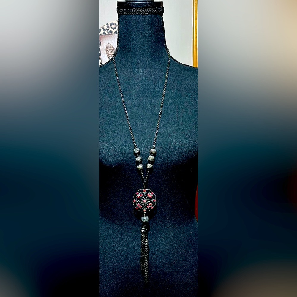 Pendant necklace with red rhinestone accents and mesh chain tassels.